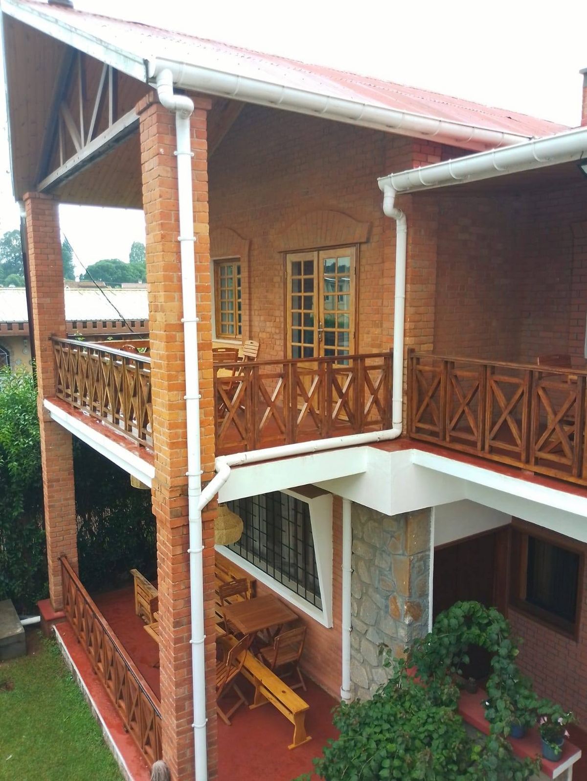 Maison en brique avec balcons en bois, terrasse et plantes